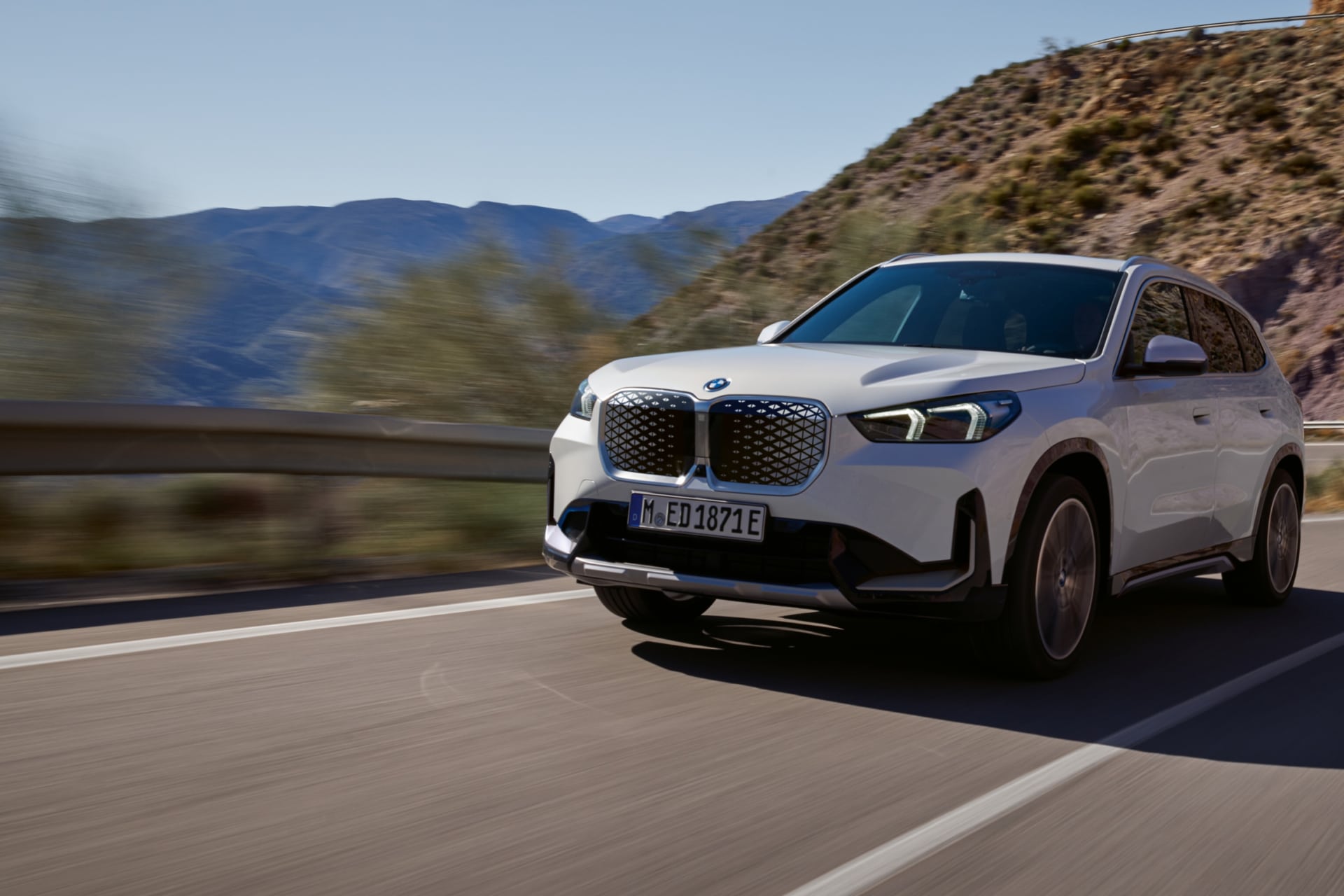 BMW iX1 לבן בנסיעה בכביש הרים